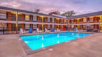 Un motel con piscina, varios balcones y zona de estar al aire libre.