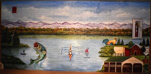 A mural with a mountain landscape, a fish, and a boat. - The Guest Lodge Gainesville (Gainesville)