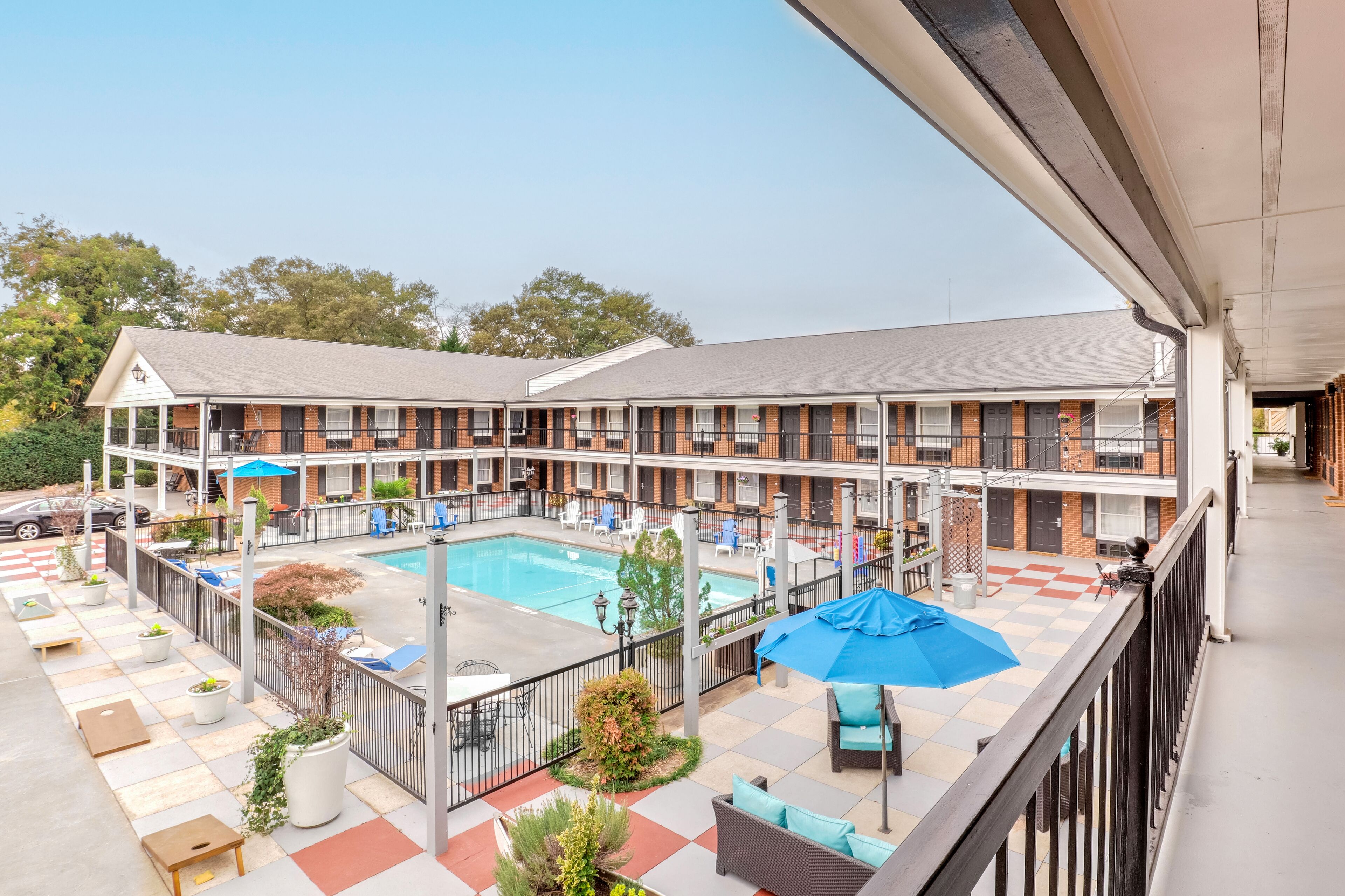 A motel with a pool area, outdoor seating, and a covered patio.