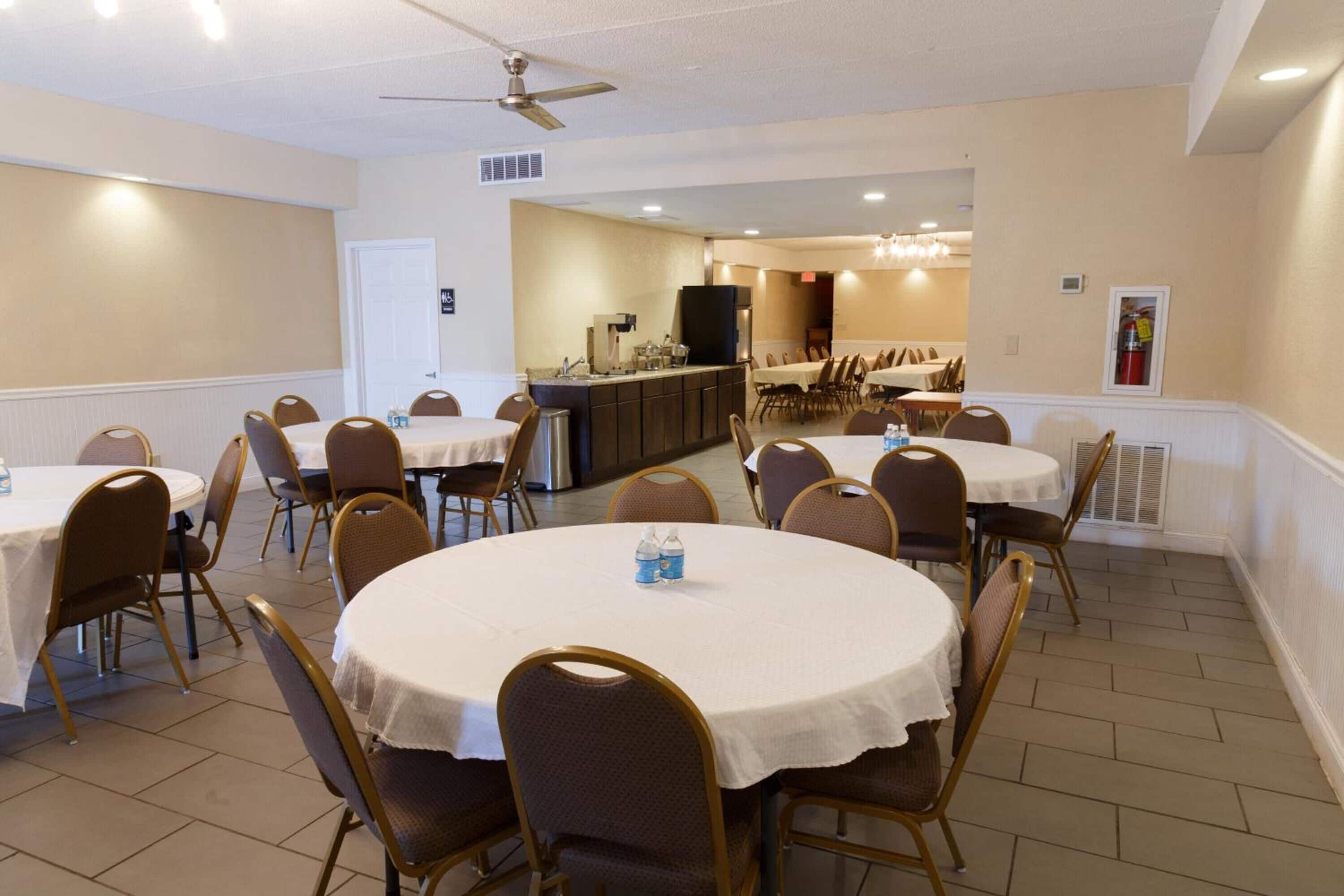 A conference room with round tables and chairs, a kitchenette, and a dining area.