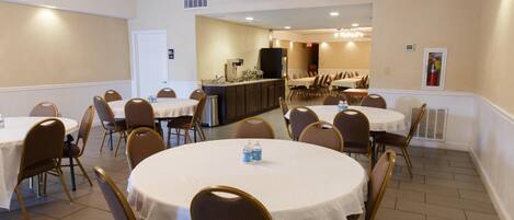 A conference room with round tables and chairs, a kitchenette, and a dining area.