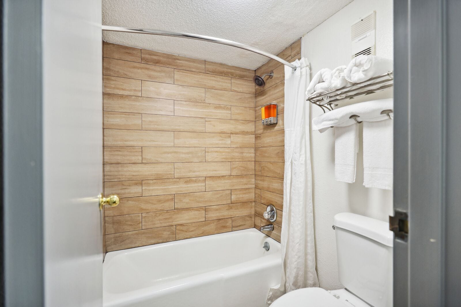 A bathroom with a wooden wall, a bathtub, a shower, and a toilet.