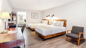 Ein Hotelzimmer mit zwei Betten, einem Schreibtisch, einem Stuhl und einer Lampe.