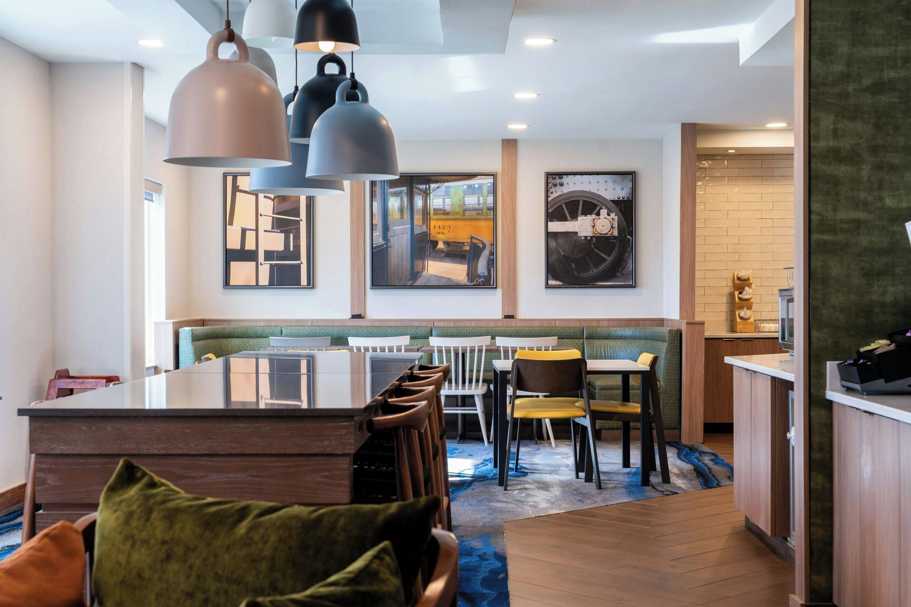 Un comedor moderno con una isla central, sillas de madera e iluminación colgante.