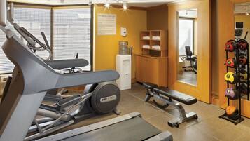 A fitness center with cardio equipment, weightlifting benches, and a rack of dumbbells.