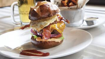 Um hambúrguer com bacon, queijo e alface sobre um prato branco.