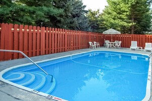 Una piscina al aire libre, sillones reclinables de piscina