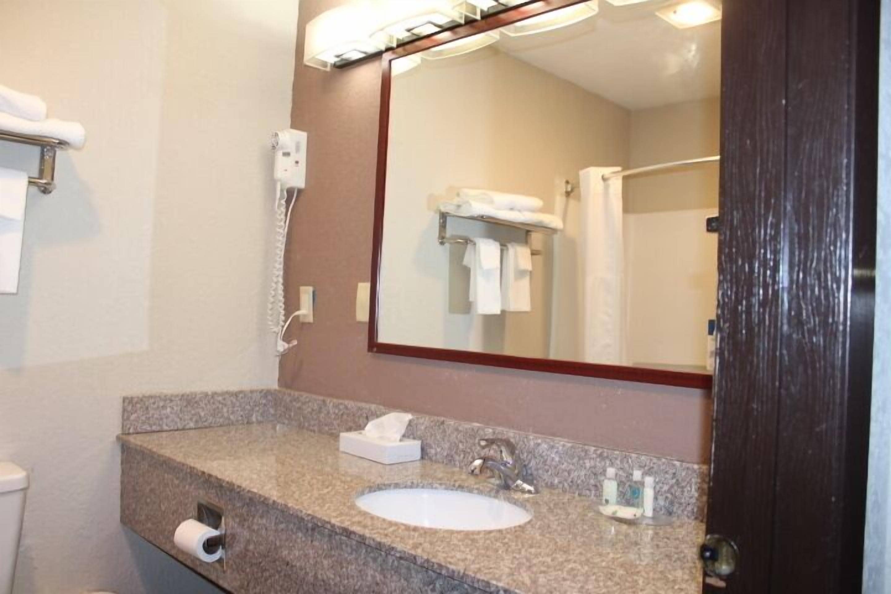 A bathroom with a granite countertop, a sink, a mirror, a towel rack, and a telephone.