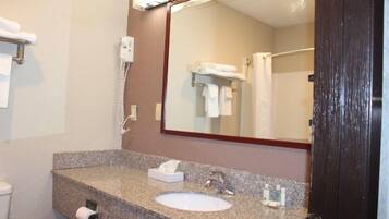 A bathroom with a granite countertop, a sink, a mirror, a towel rack, and a telephone.