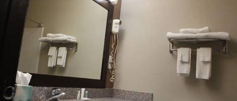 A bathroom with a sink, mirror, towel rack, toilet, and a towel dispenser.