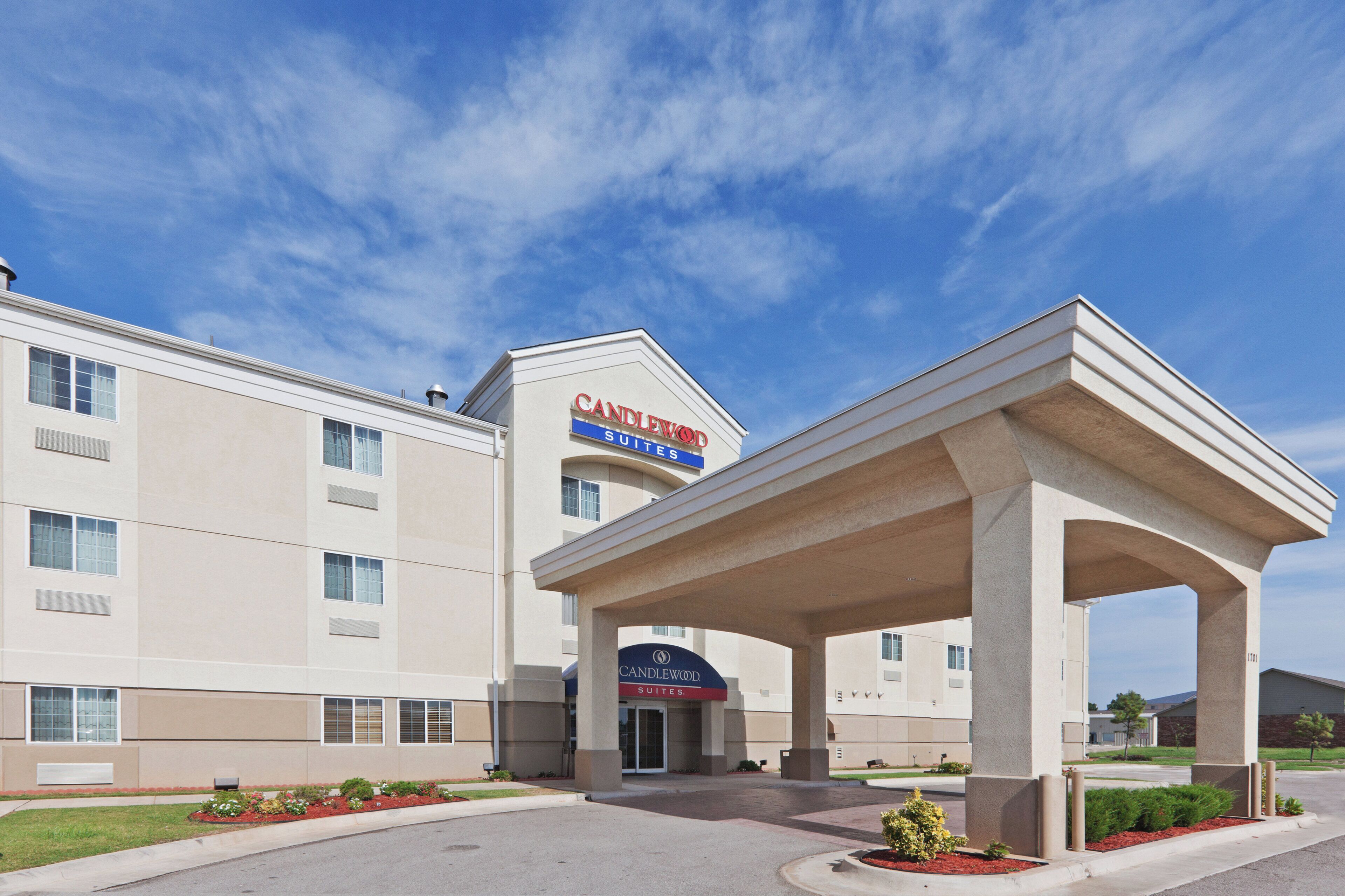 A hotel with a modern facade, a covered entrance, and a clear sky.