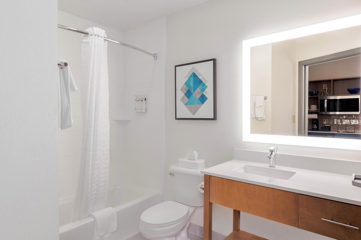 Un baño moderno con ducha, inodoro, lavabo y un espejo grande.