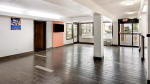 A hallway with a wooden floor, a door, and a wall-mounted sign. - Motel 6 Macon, GA (Macon)