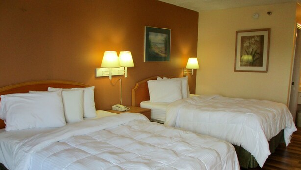 A hotel room with two beds, each with white bedding and pillows. There are two bedside lamps on the nightstands. - Motel 6 Macon, GA (Macon)