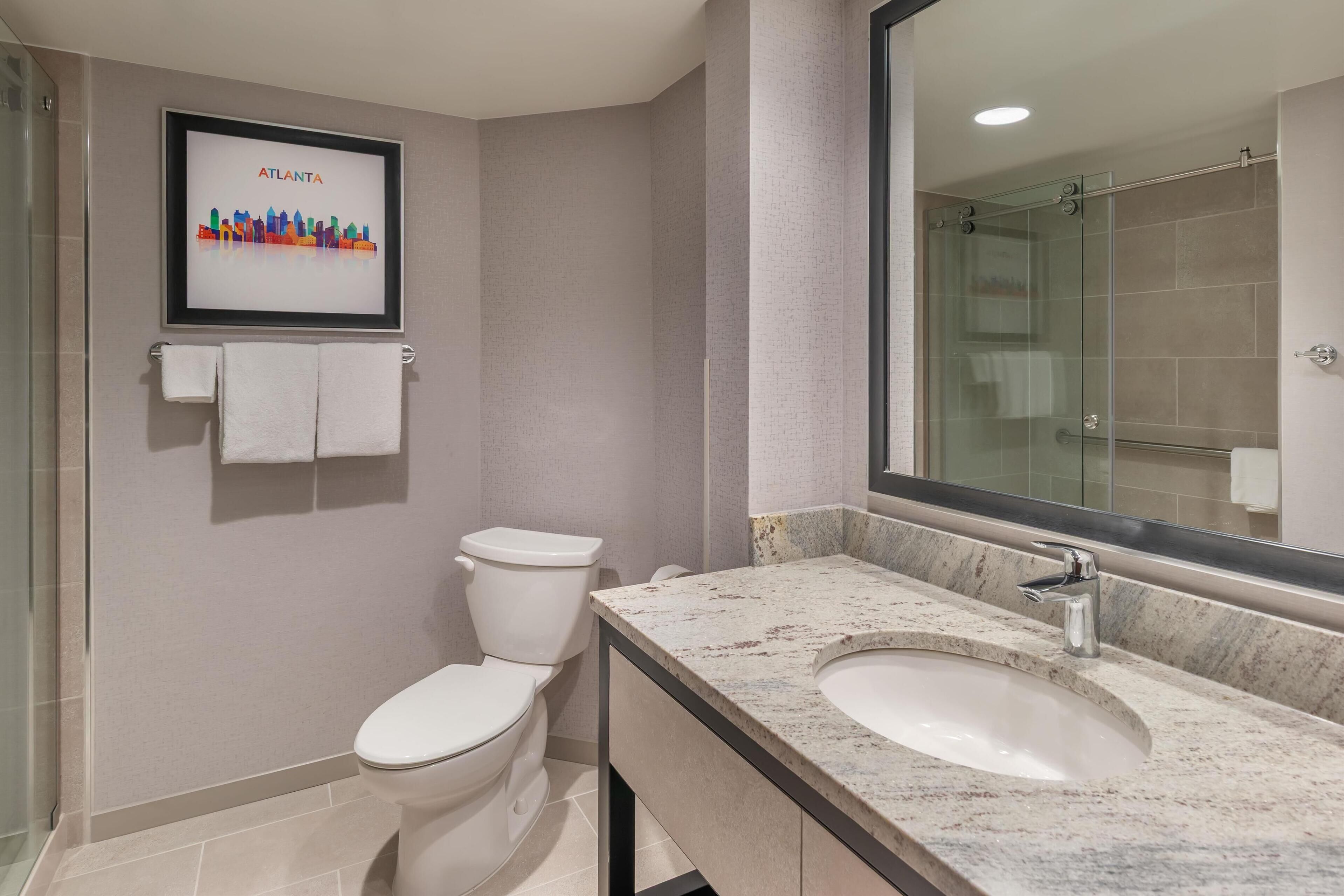 A modern bathroom with a toilet, sink, and a large mirror.