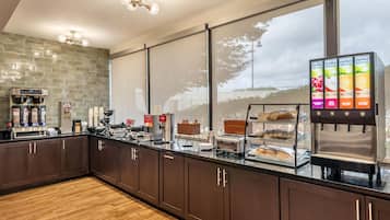 Cozinha moderna com espaço para café, exposição de frutas e vista através de grandes janelas.