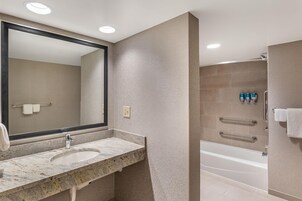 Un baño con lavamanos de mármol, un espejo grande y una bañera.