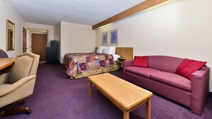 Ein Hotelzimmer mit Bett, Sofa, Schreibtisch und Stuhl.