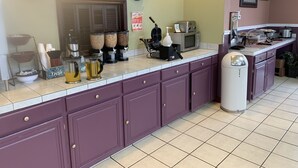 Ein Frühstücksbuffet mit Schildern, Kaffeeautomaten, einem Toaster und einer Mikrowelle.