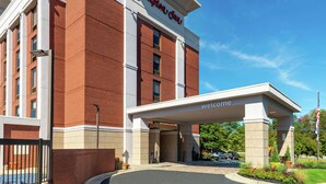 A Hampton Inn with a 'Welcome' sign, brick facade, and a covered entrance. - Hampton Inn Greensboro-Airport (Greensboro)