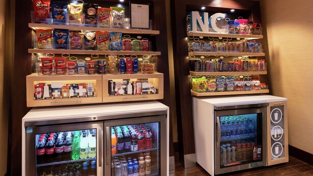 A vending machine with snacks and drinks, and a freezer with beverages. - Hampton Inn Greensboro-Airport (Greensboro)