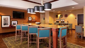 A modern kitchen with a central island, bar stools, and a seating area. - Hampton Inn Greensboro-Airport (Greensboro)