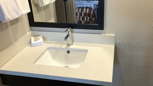 Een badkamer met een witte wastafel, een spiegel en een handdoekrek.