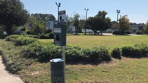 A dog waste station with a sign instructing to clean up after your dog.