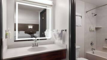 A modern bathroom with a large mirror, a sink, a toilet, and a shower area.
