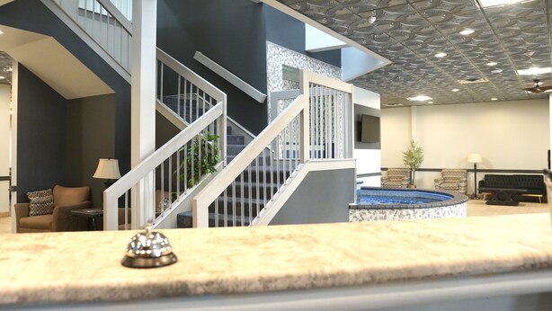 A modern interior with a staircase, a pool, and a reception area. - American Inn & Suites Waterford (Waterford)