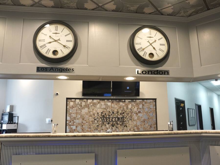 A reception area with two clocks labeled 'Los Angeles' and 'London', a welcome sign, and a counter with a decorative tile backsplash.