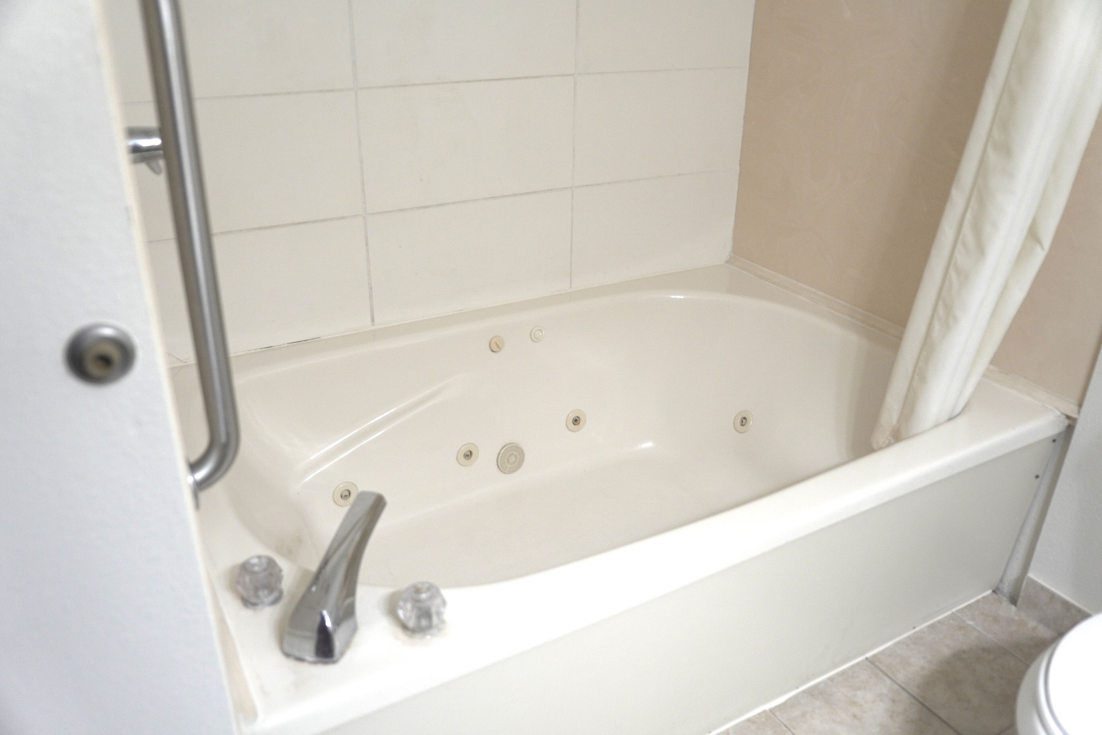 Une salle de bain avec une baignoire blanche, un rideau de douche et des toilettes.