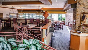 A restaurant with high tables, cushioned booths, and a brick wall with a framed picture. - DoubleTree by Hilton Hotel Oak Ridge - Knoxville (Oak Ridge)