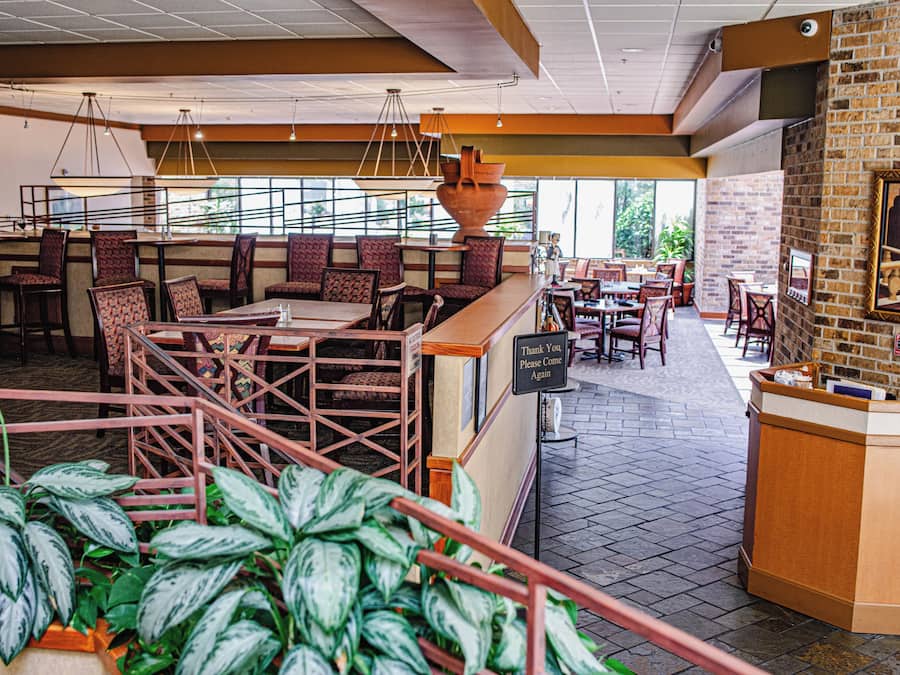 A restaurant with high tables, cushioned booths, and a brick wall with a framed picture.