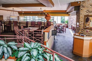 A restaurant with high tables, cushioned booths, and a brick wall with a framed picture. - DoubleTree by Hilton Hotel Oak Ridge - Knoxville (Oak Ridge)