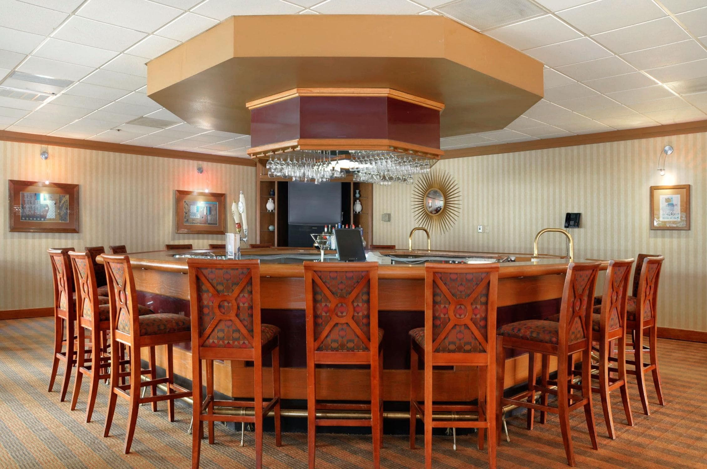 Un salón de conferencias de hotel con una gran mesa ovalada, varias sillas, una zona de bar y un candelabro.