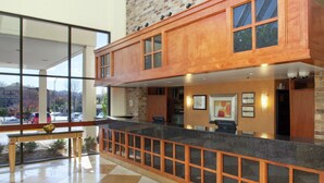 A reception area with a check-in counter, a bench, and a view of the outside. - DoubleTree by Hilton Hotel Oak Ridge - Knoxville (Oak Ridge)