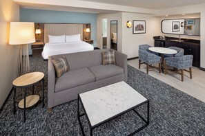 A hotel room with a bed, sofa, coffee table, desk, and a small kitchenette. - DoubleTree by Hilton Hotel Oak Ridge - Knoxville (Oak Ridge)