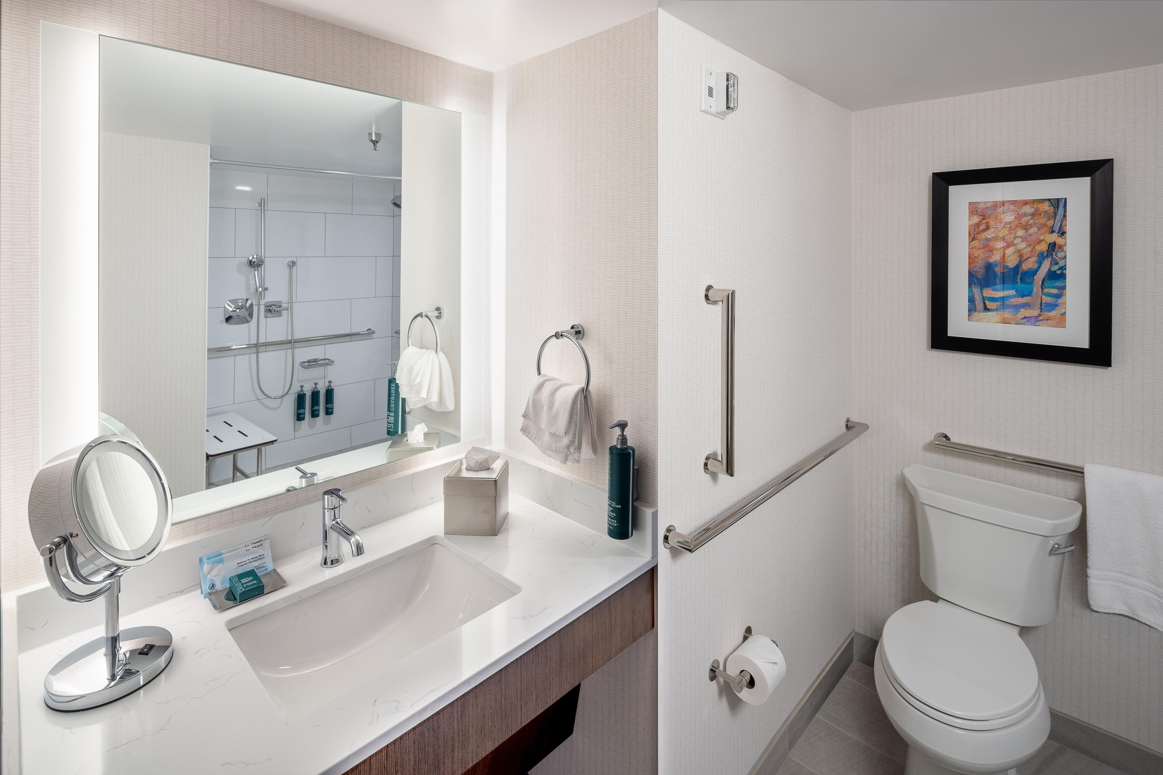 A modern bathroom with a large mirror, sink, and toilet.