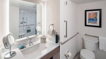 A modern bathroom with a large mirror, sink, and toilet.