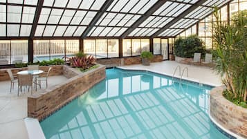 Una piscina techada, una piscina al aire libre, sombrillas