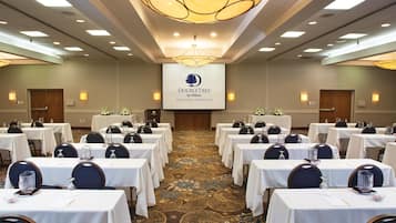 Une salle de conférence équipée de plusieurs tables, de chaises et d’un grand écran affichant le logo de la chaîne DoubleTree by Hilton.