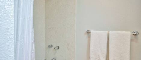 A bathroom with a bathtub, shower, and two towels hanging on a rack.