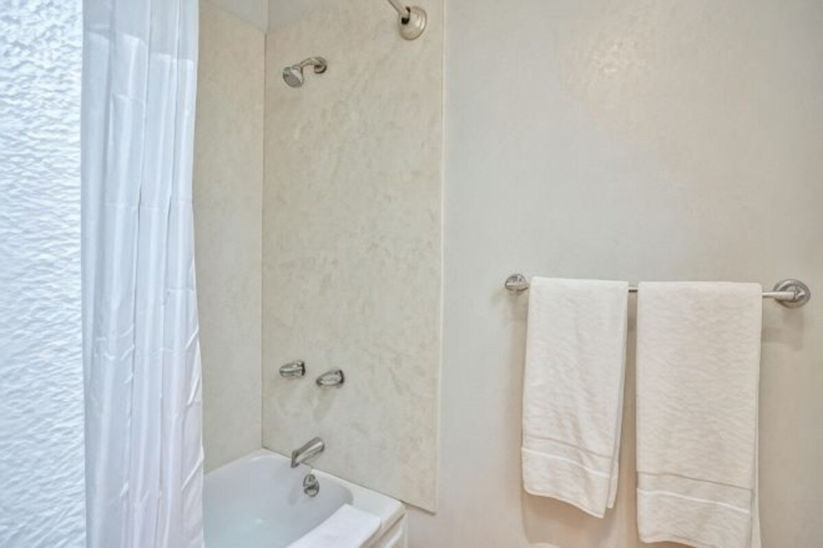 A bathroom with a bathtub, a shower, and two towels hanging on a rack.