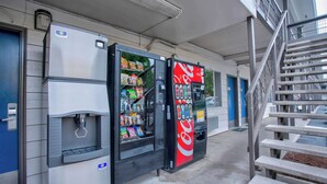 Un espace comprenant des distributeurs automatiques, notamment un distributeur de Coca-Cola, un distributeur d’eau et un distributeur de collations.