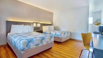Habitación de hotel con dos camas, un escritorio y una silla.