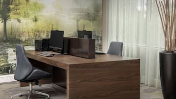 A modern office desk with a computer setup, a chair, and a large window with a view of trees.