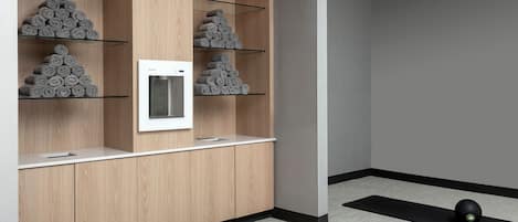 A modern bathroom with wooden cabinetry, a built-in toilet, and a towel rack with neatly rolled towels.