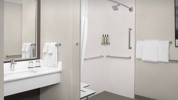 Un baño moderno con ducha, lavamanos y espejo.