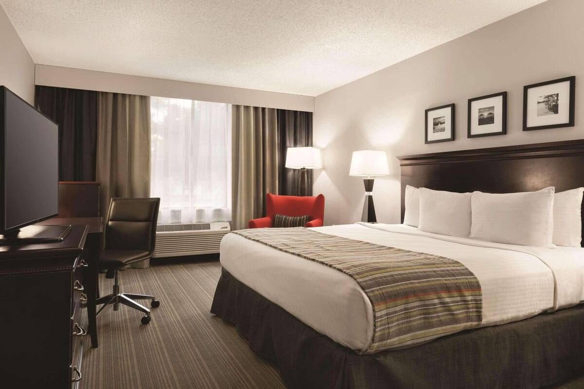 A hotel room with a bed, desk, chair, and two lamps.